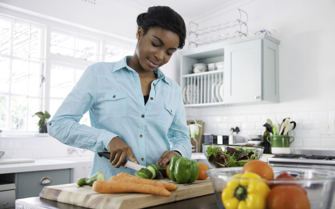 Person slicing vegetables and fresh food in kitchen, banner image that leads to tips for building a healthy eating plan